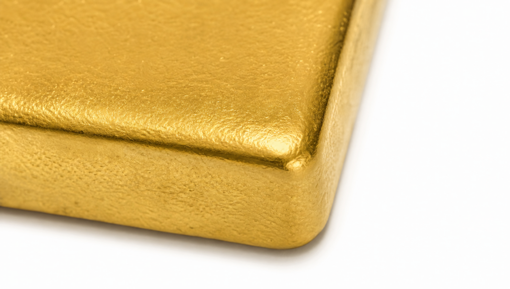 Macro detail of an unbranded gold bullion bar corner and metallic surface.